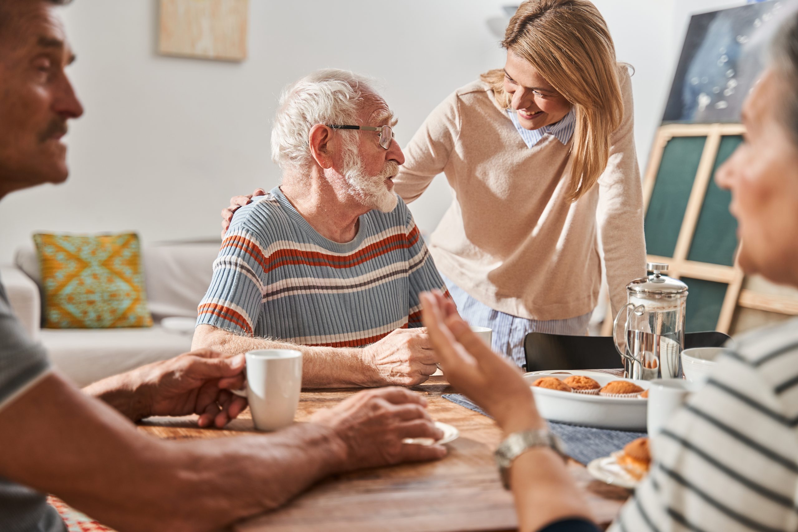 Senior man and embracing him at the shoulder while working with group of elderly people