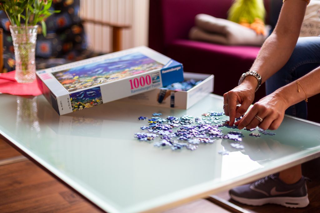 junge Frau puzzelt am Couchtisch, Beschäftigung Wohneinrichtung